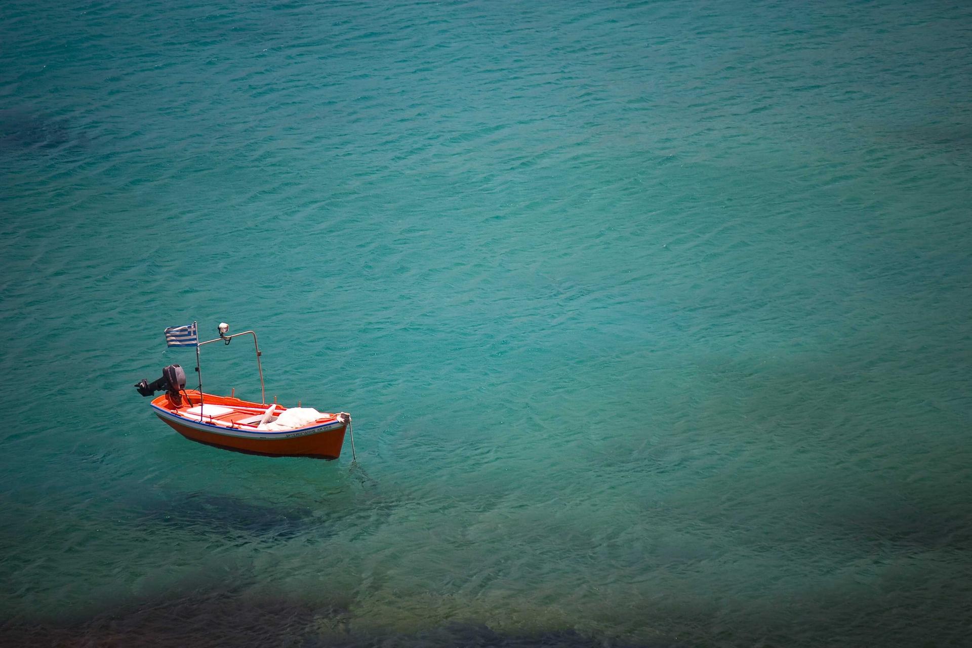 Barca roja flotando sobre agua turquesa, vista desde arriba